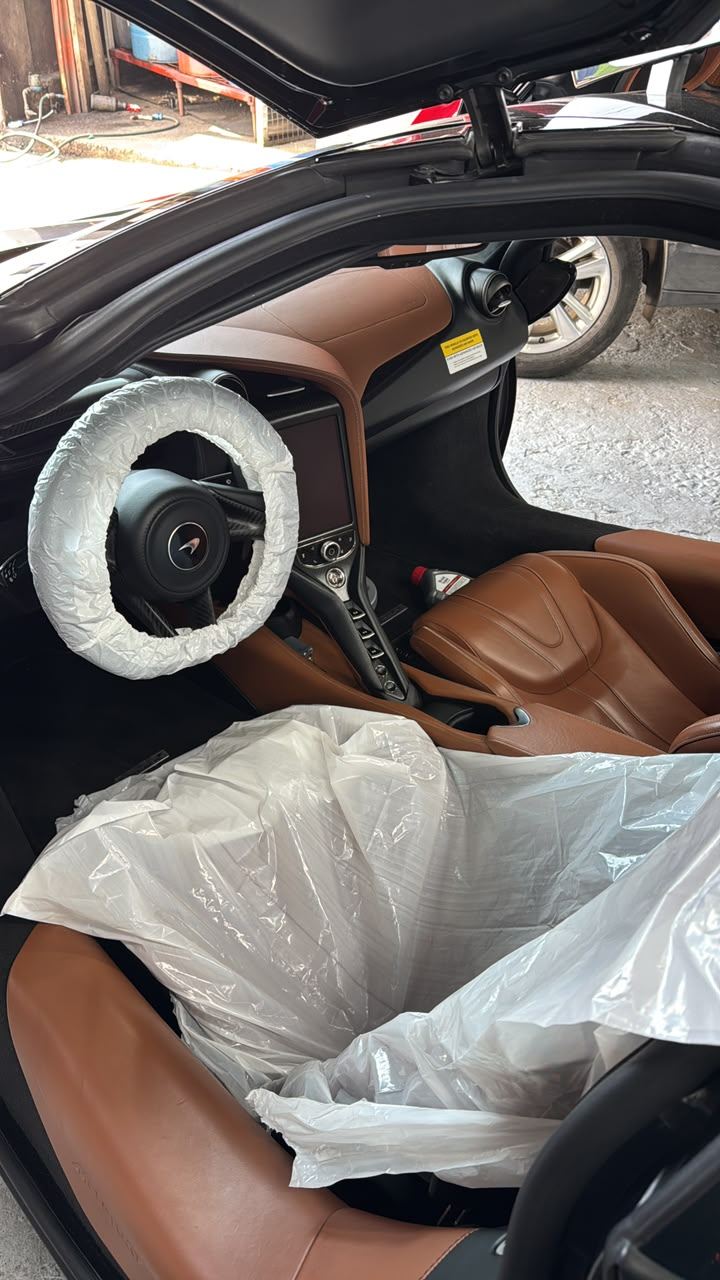 Detalle del interior de un McLaren 720S en servicio, volante y asientos protegidos