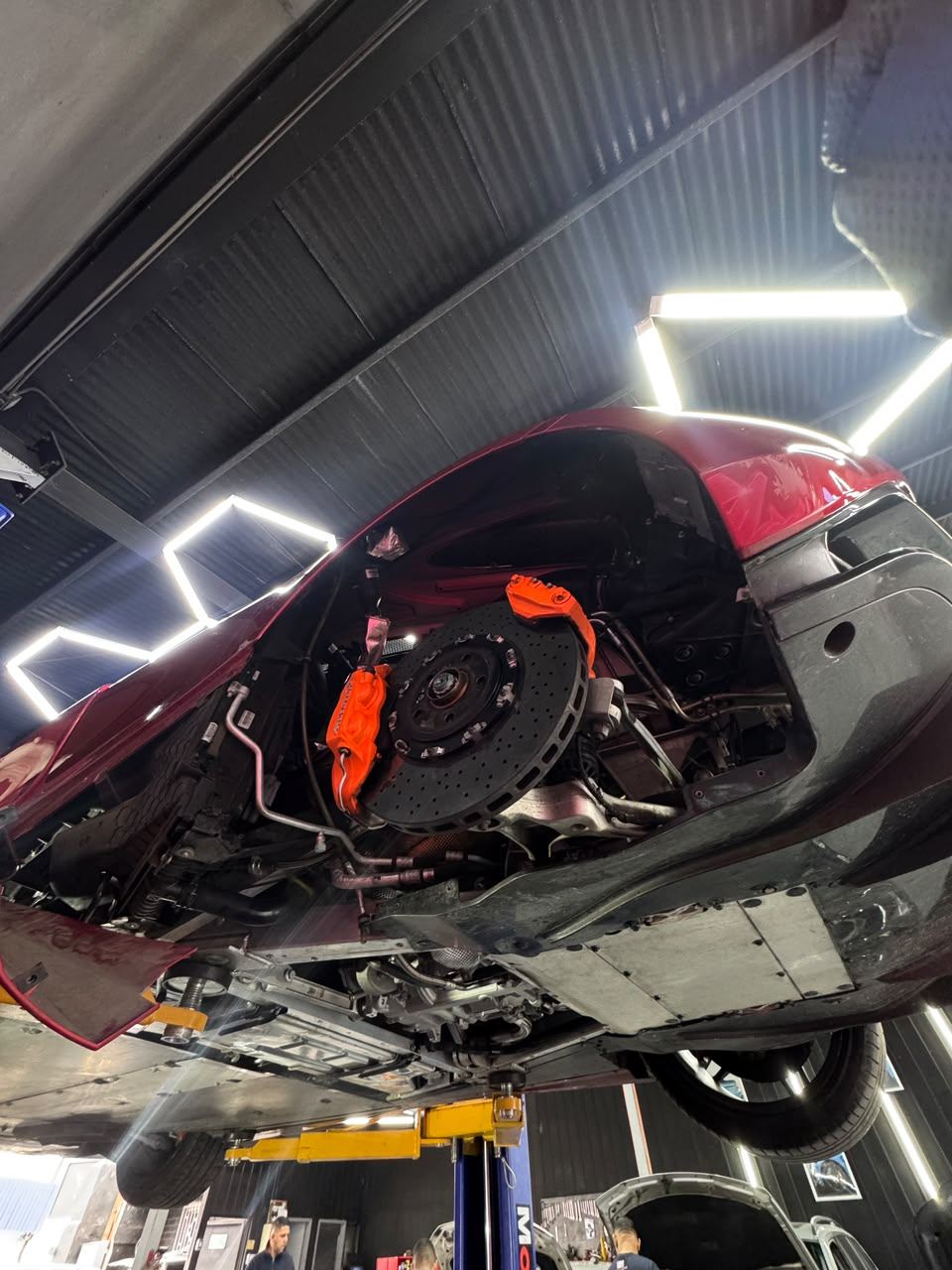 Detalle de frenos y suspensión de un McLaren 720S elevado en el taller