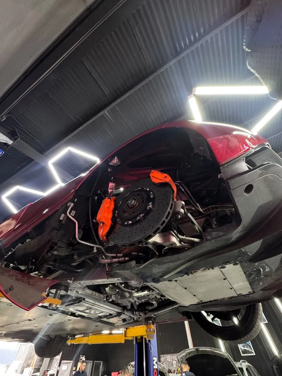 Detalle de frenos y suspensión de un McLaren 720S elevado en el taller